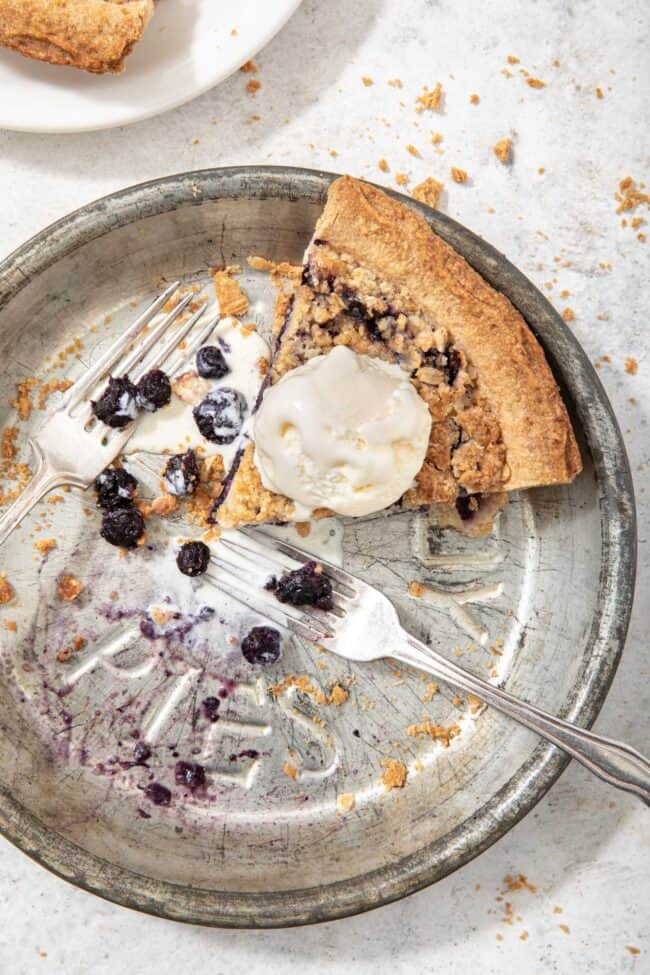 an aluminum pie tin with a slice of pie in it with a scoop of vanilla ice cream