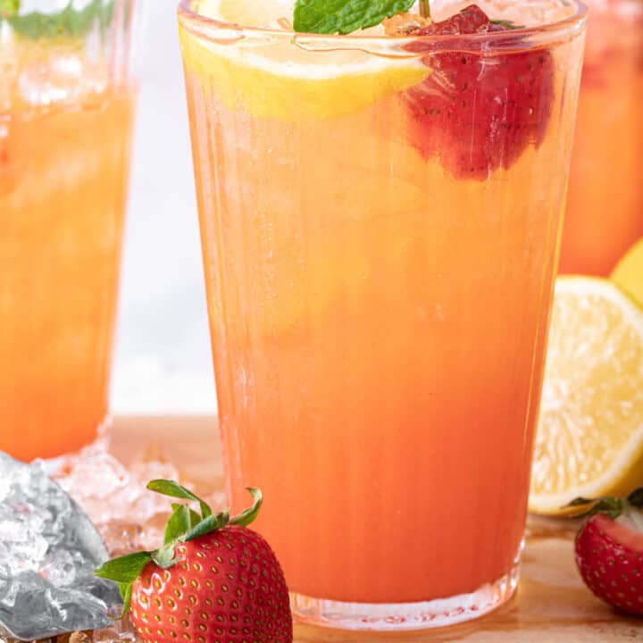 3 glasses filled with strawberry lemonade and garnished with strawberries, lemon slices and mint sprigs