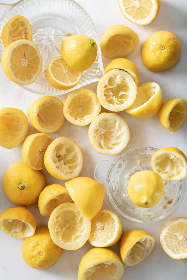 two glass juicers sit next to many squeezed lemon halves