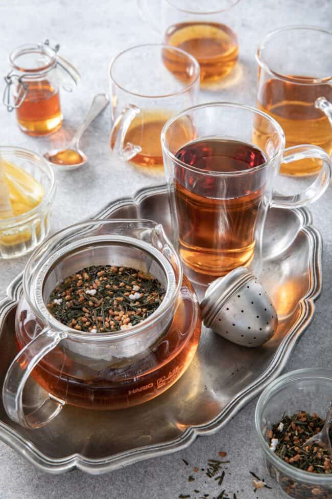 Clear glass tea pot and clear glass tea cups filled with tea to measure how many ounces in a gallon