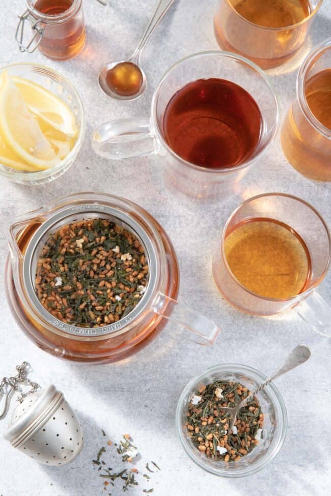 Clear glass tea pot and clear glass tea cups filled with tea to measure how many ounces in a gallon