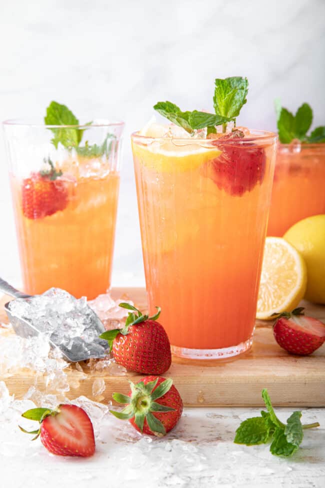 Three clear glasses filled with Strawberry lemonade.