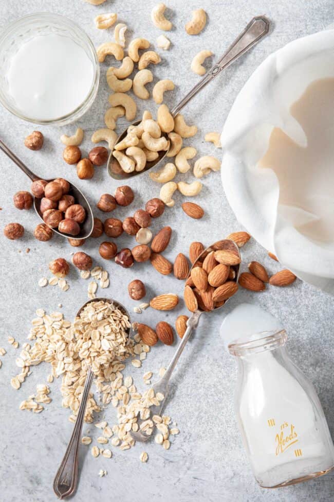 cashews, filberts, almonds, oats and shredded coconut scattered next to a bowl filled with cheese cloth and almond milk for how many tablespoons in 1/3 cup