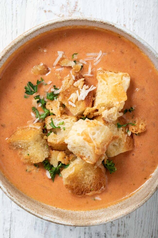 A bowl of soup garnished with Parmesan cheese croutons.