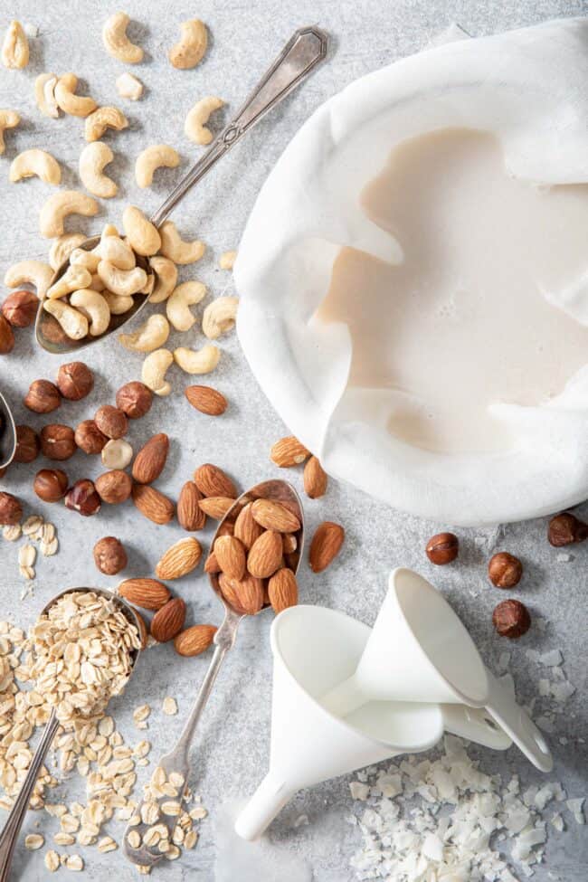 cashews, filberts, almonds, oats and shredded coconut scattered next to a bowl filled with cheese cloth and almond milk for how many tablespoons in 1/3 cup