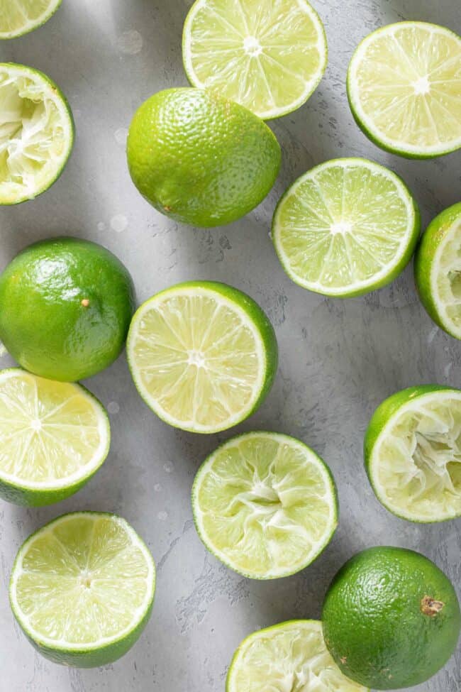 many citrus fruits cut in half scattered on a gray board