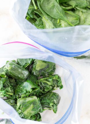 A white ice cube tray filled with green vegetable leaves.