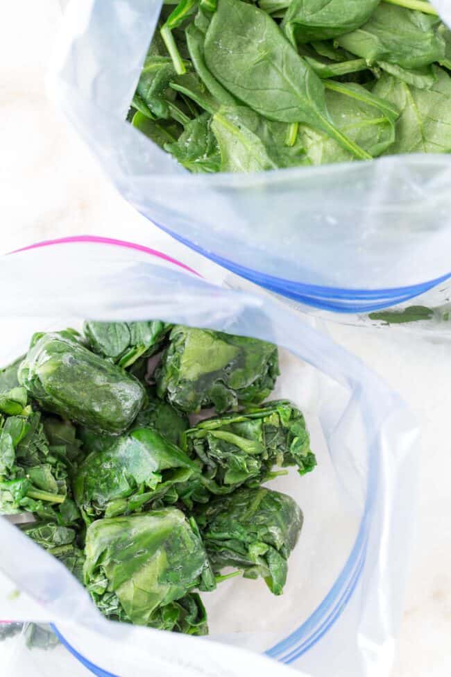 Two freezer bags filled with frozen spinach.