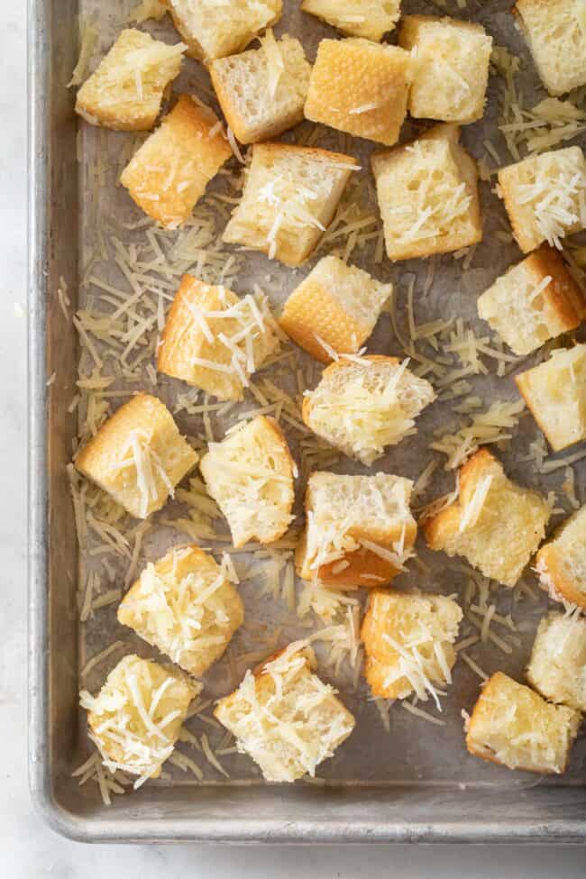 A baking sheet filled with Parmesan cheese croutons.