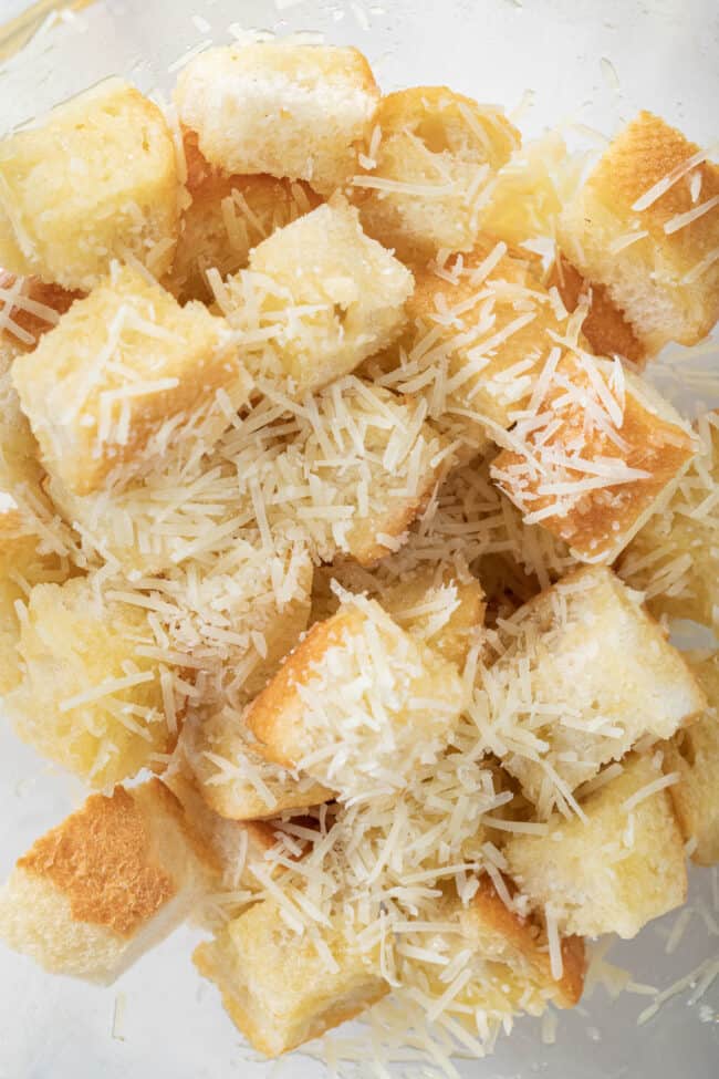 Pieces of cubed bread with grated cheese scattered over them.