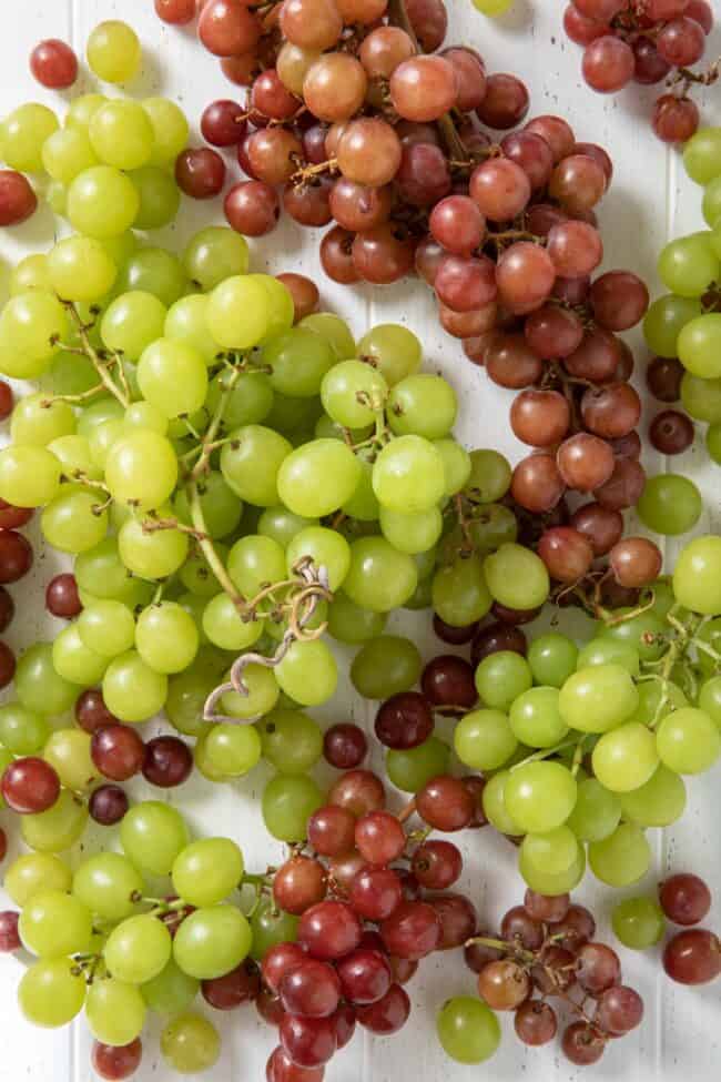 Large bunches of red and green grapes on a white board