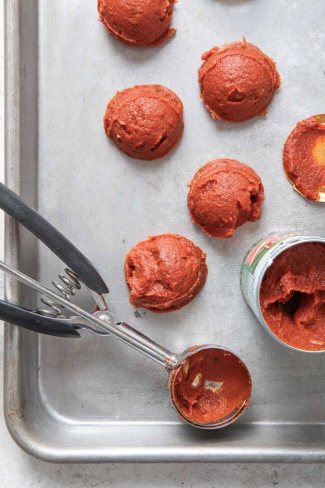 A melon scoop sits next to a can of red sauce.