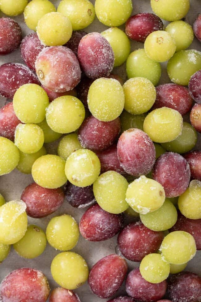 Dozens of frozen grapes (red and green) on a cookie sheet