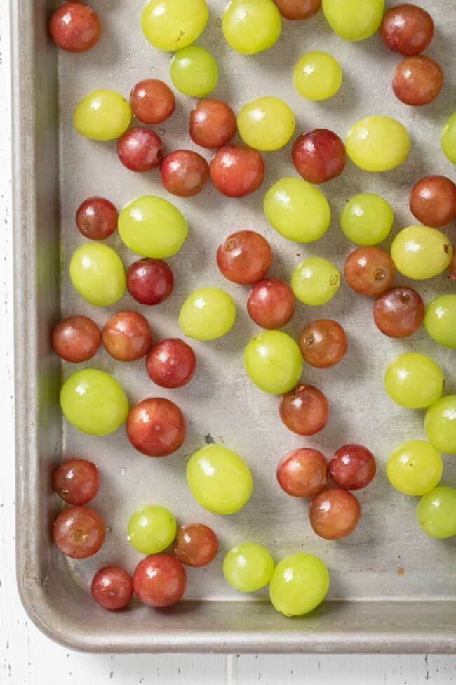 Red and green fruit on a cookie sheet.