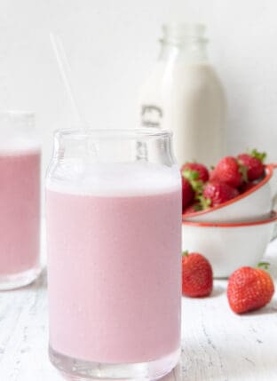 Two clear glasses filled with strawberry milk.