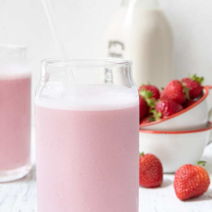 Two clear glasses filled with strawberry milk.