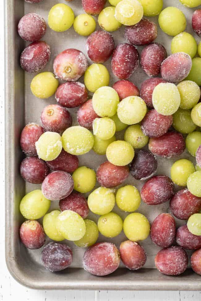 Cookie sheet filled with frozen grapes (red and green).