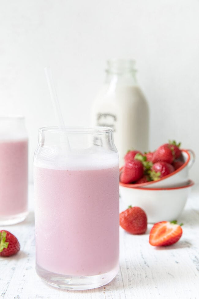 Two clear glasses filled with strawberry milk.