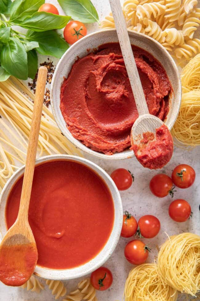 Two white bowls filled with pomodoro and dried noodles and fresh parsley sit next to the bowls.