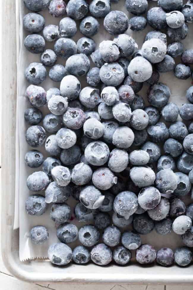 A cookie sheet filled with frozen blueberries (for how to freeze blueberries)