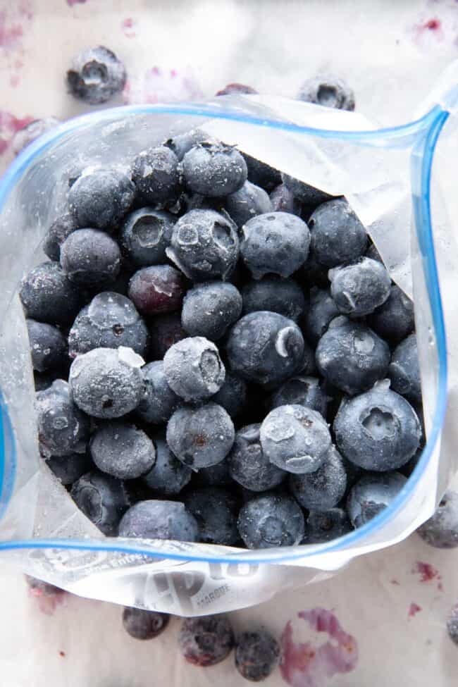 A plastic freezer bag filled with frozen blueberries.