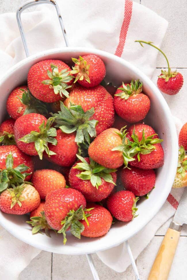 A white colander filled with fresh fruit.