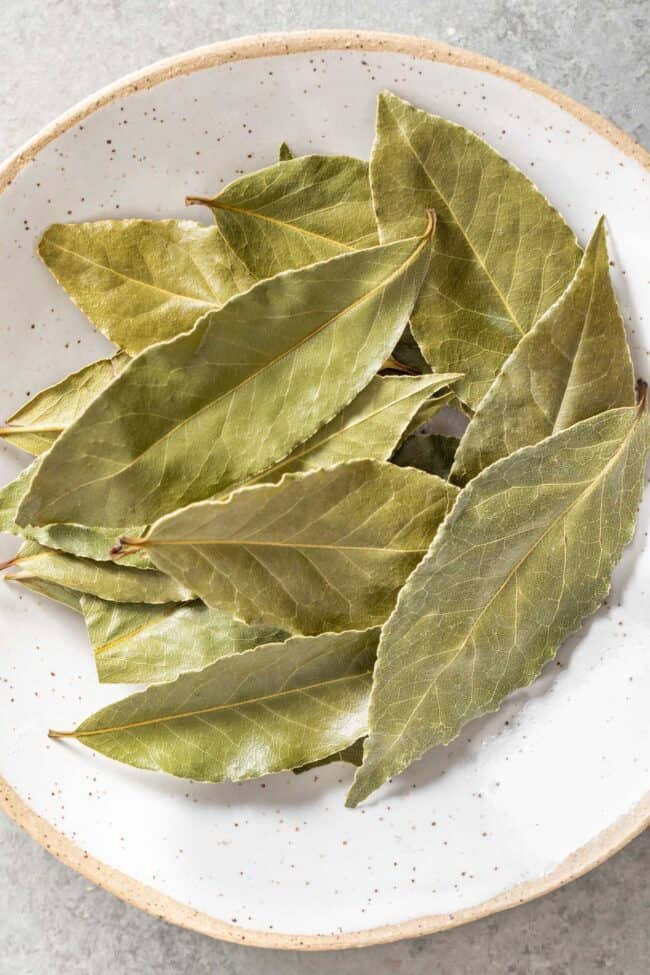 A white bowl filled with dried Turkish bay leaves