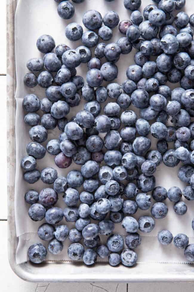 Fresh fruit scattered on a cookie sheet lined with parchment paper.