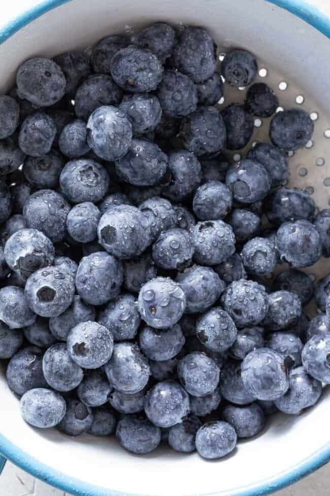 Fresh blueberries in a blue and white colander