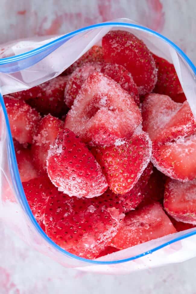 A plastic freezer bag filled with frozen strawberries.