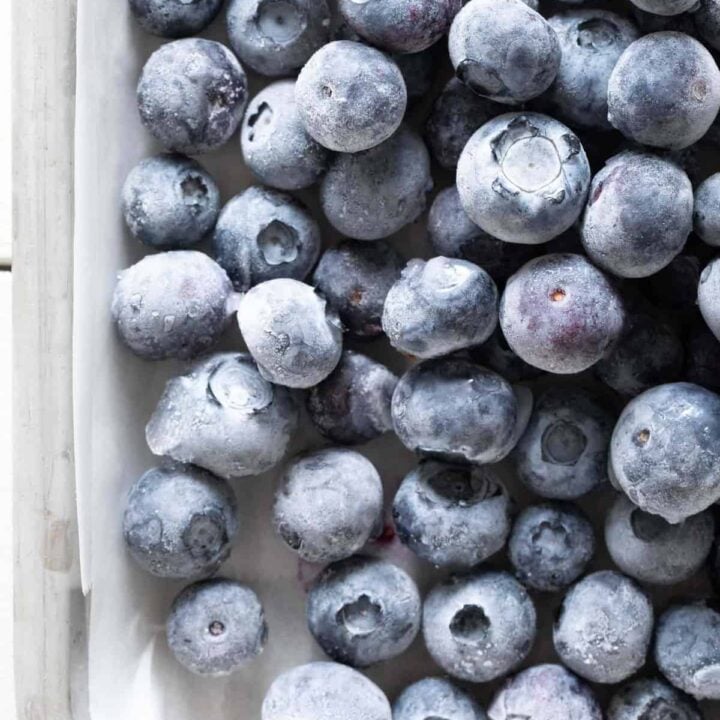 A cookie sheet filled with frozen blueberries.