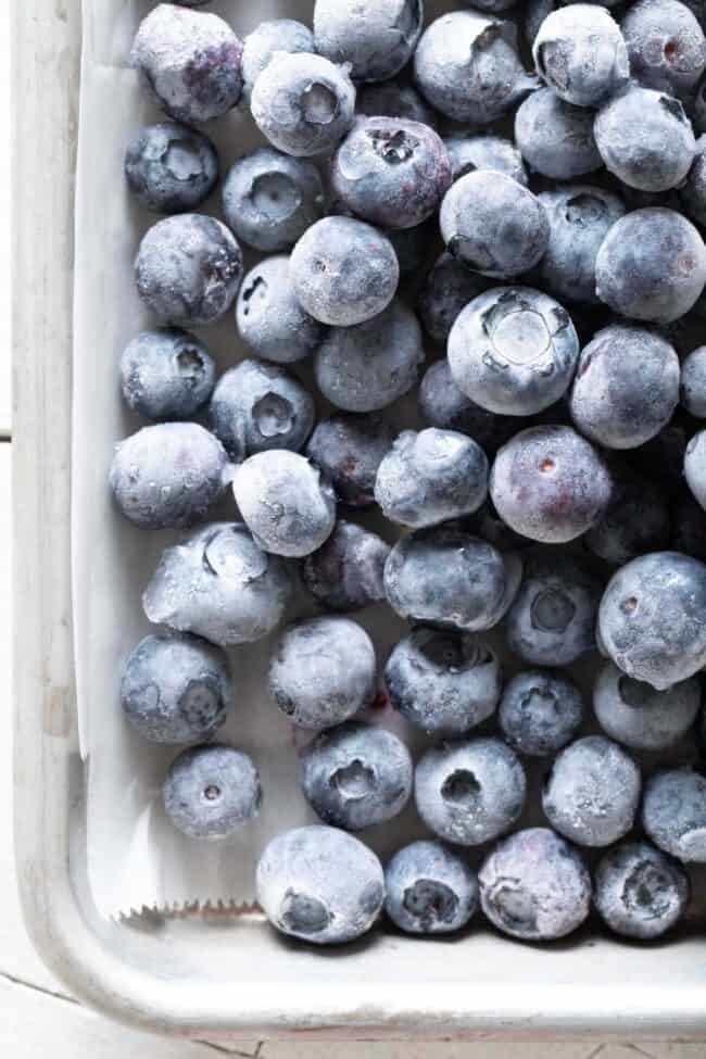 A cookie sheet filled with frozen blueberries for how to freeze blueberries.