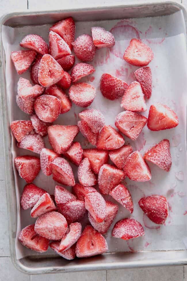 A baking sheet filled with frozen strawberries for how to freeze strawberries
