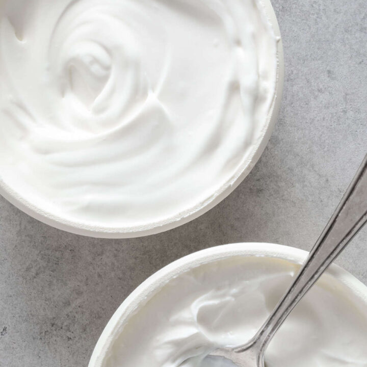 Two containers filled with creme fraiche. A spoon rests in one of the containers.