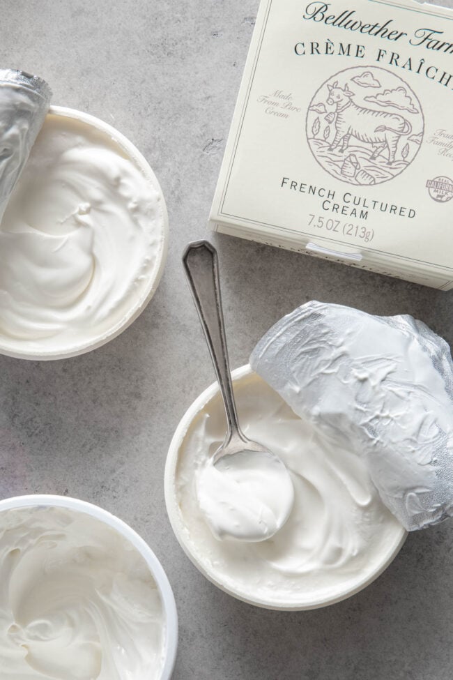 Three containers filled with creme fraiche. A spoon rests inside one of the containers. 