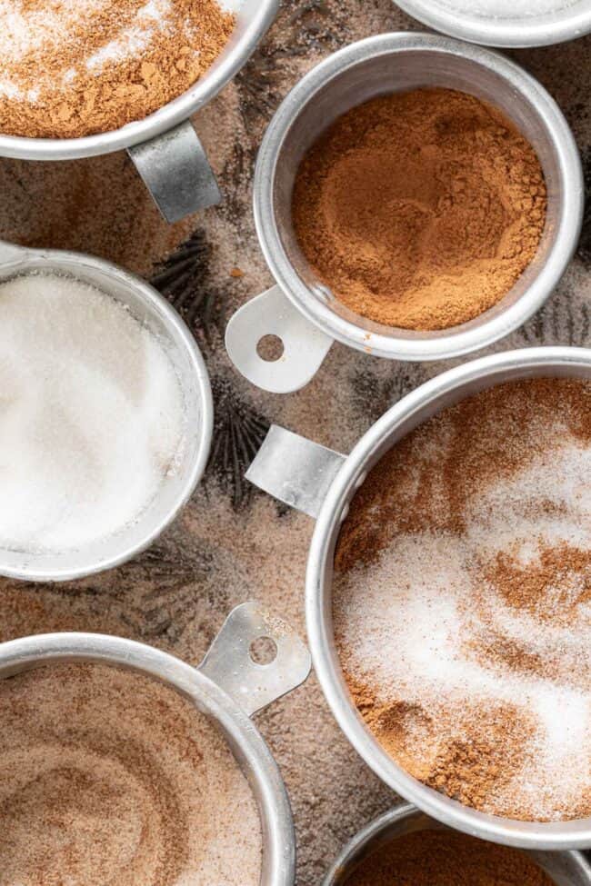 Aluminum measuring cups filled with spices.