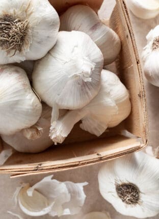 A small wood box filled with garlic bulbs.