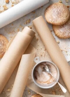 Three rolls of parchment paper scattered on a tray with cookies next to them.