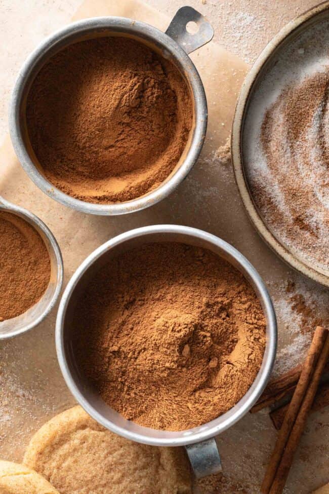 Aluminum measuring cups filled with ground spices. 