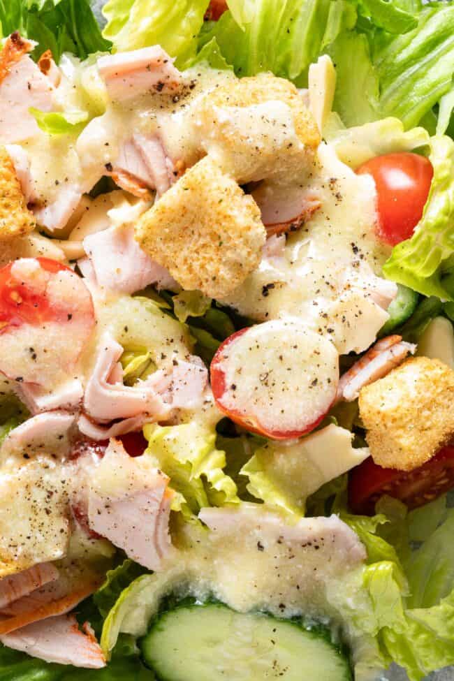 A clear glass plate filled with salad drizzled with vinaigrette.