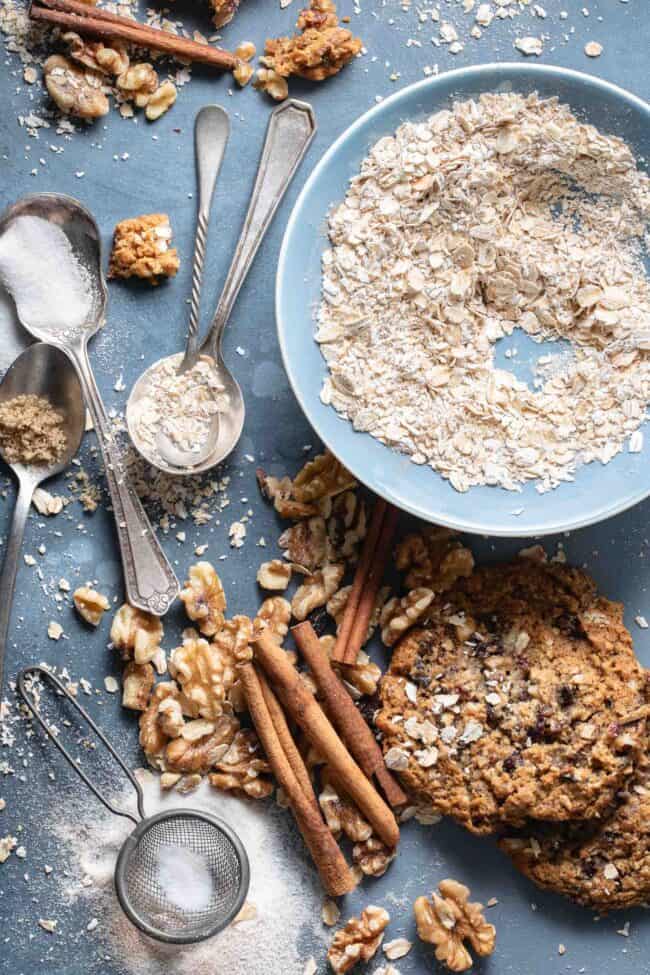 A small blue bowl filled with raw oats next to spoons filled with white sugar and brown sugar for how many tablespoons in 2/3 cup.