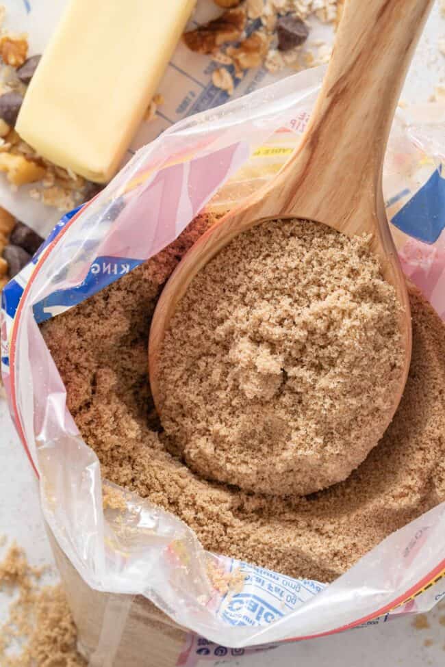 A wooden spoon rests in a bag of brown sugar (for brown sugar substitutes).