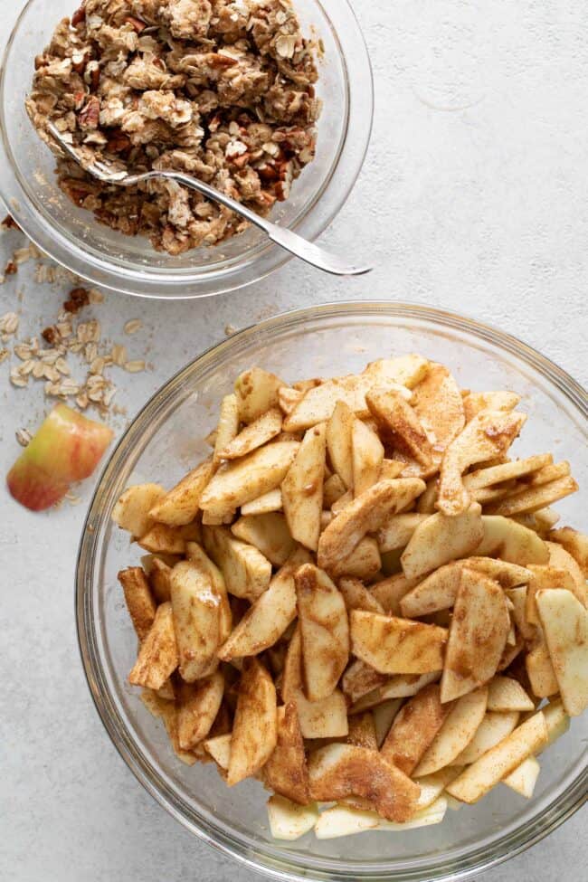 Two glass mixing bowls with oats and fruit.