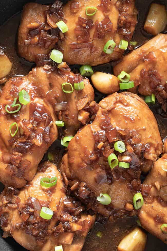 Six pieces of Filipino Adobo chicken simmering in a skillet.