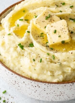 A white and brown bowl filled with mashed potatoes.