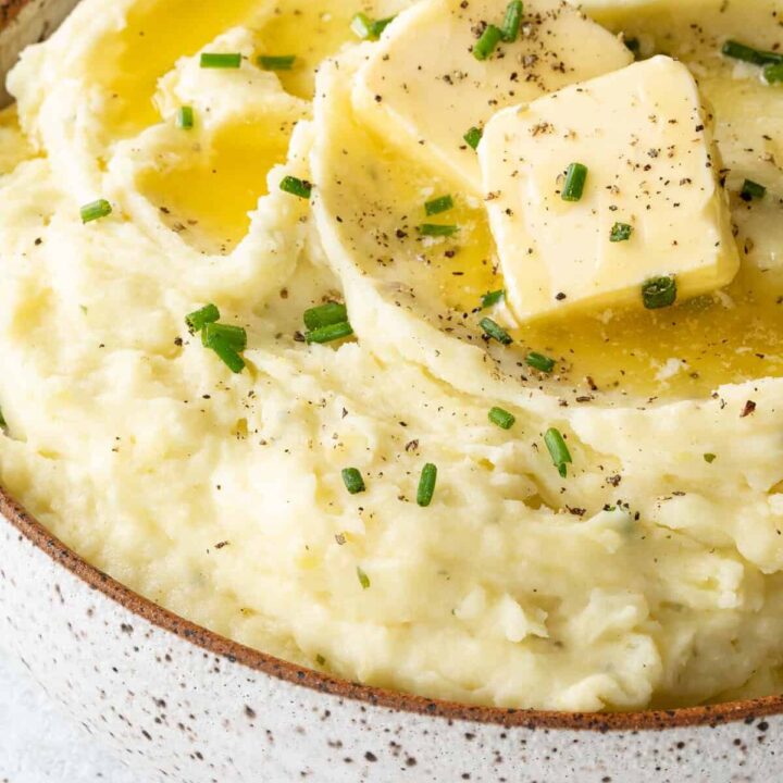 A white and brown bowl filled with mashed potatoes.