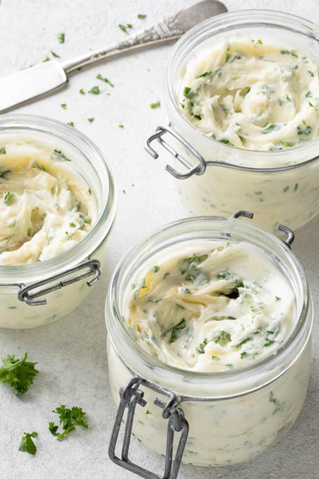 Three glass mason jars filled with garlic butter.