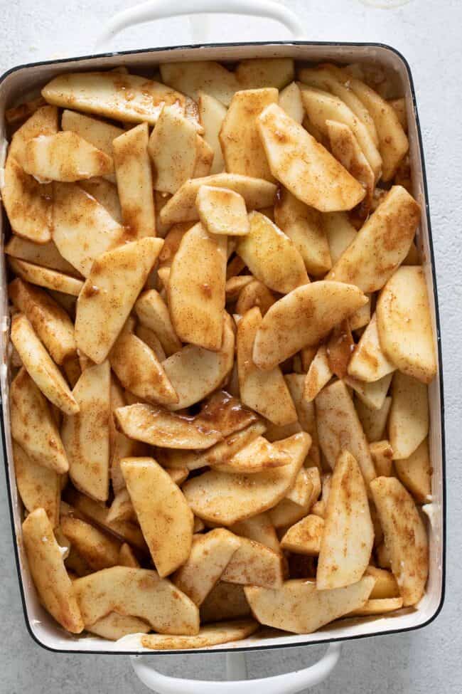 A white baking dish filled with sliced apples.