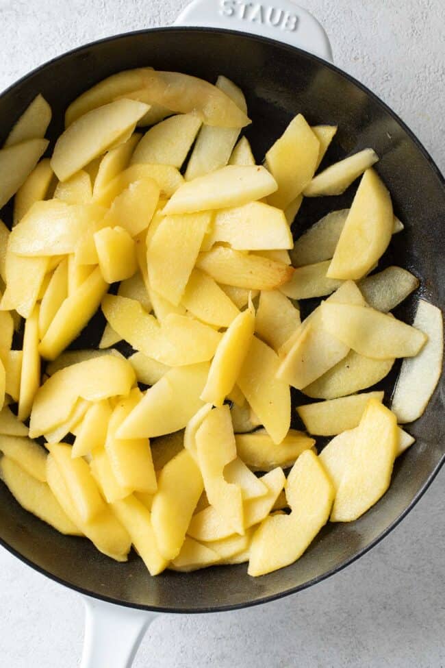 A black skillet filled with sliced fruit.