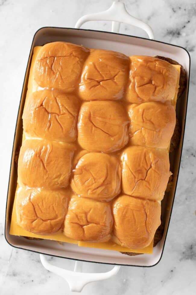 A white baking dish filled with dinner rolls stuffed with scrambled eggs and sausage patties.